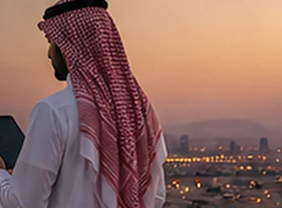 A business owner holding a tablet at dusk.