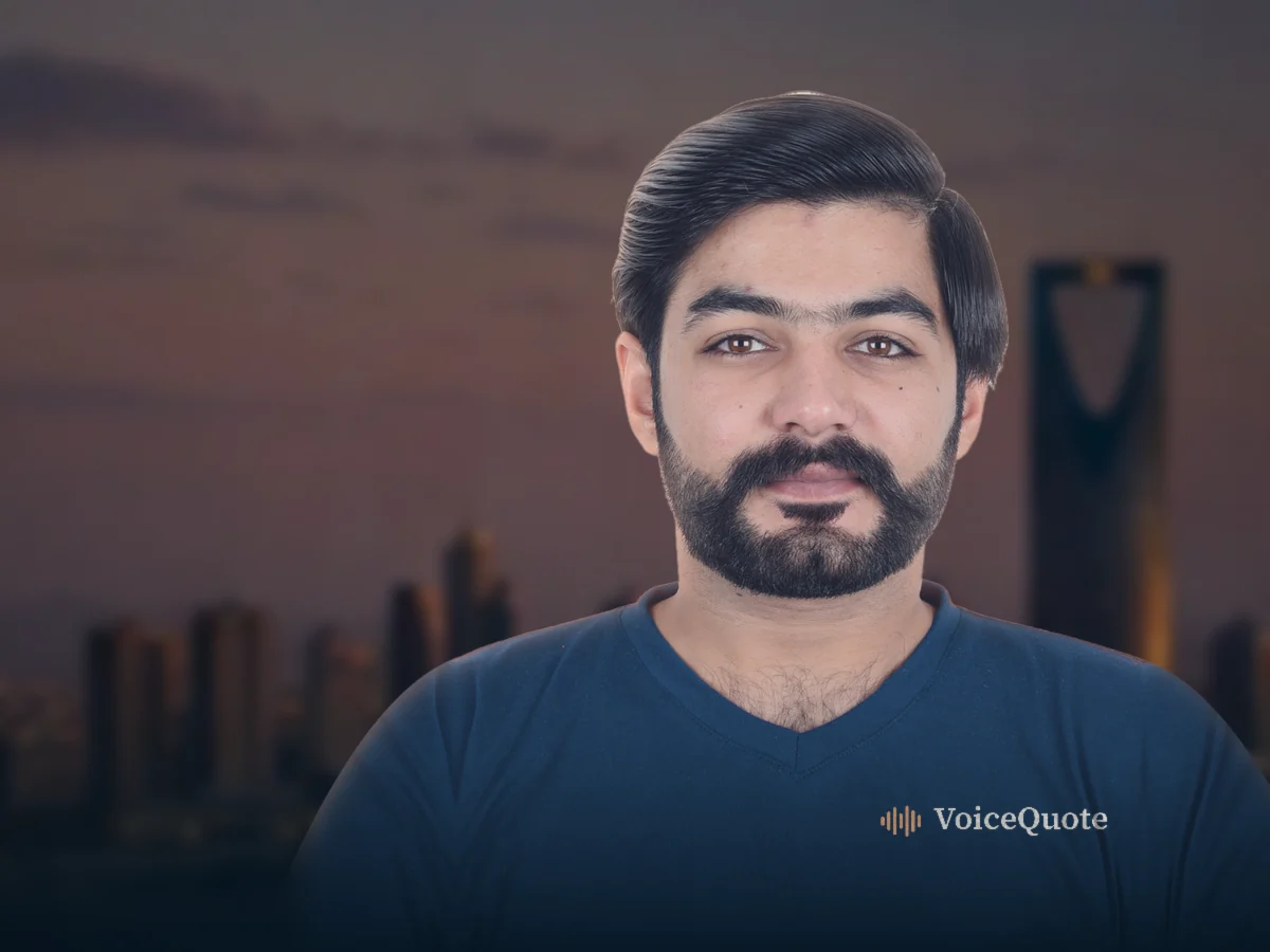 A man in a navy VoiceQuote T-shirt, with the city skyline at dusk behind him.